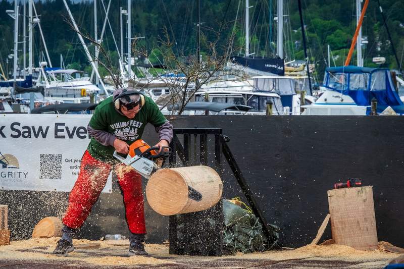 Man with a chainsaw cuts a slice off the end of a log