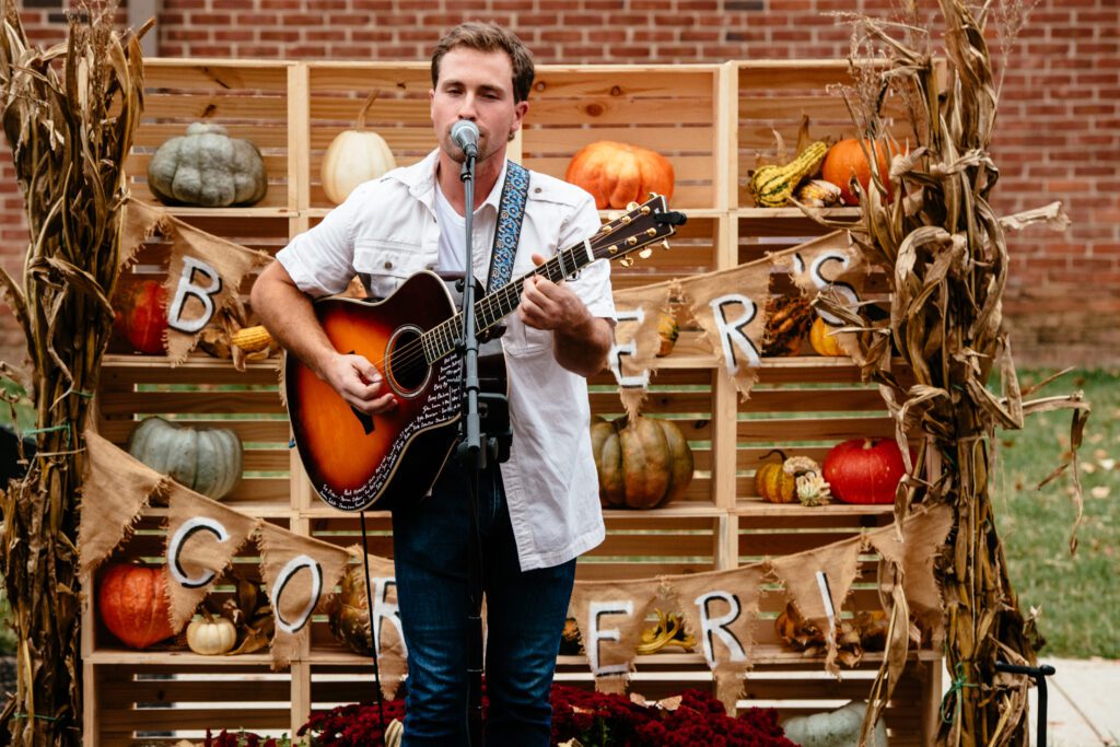 A performer at the Grains & Grits Festival. Photo credit: Tennessee Tourism A performer with a guitar in front of a fall decorated stage at the Grains and Grit Festival.