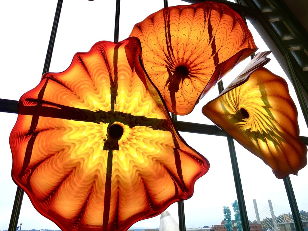 Large round orange and yellow art glass by Dale Chihuly in a half oval window.