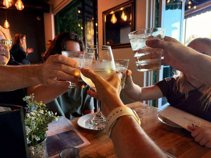 A family toasting with wine and water at a restaurant.