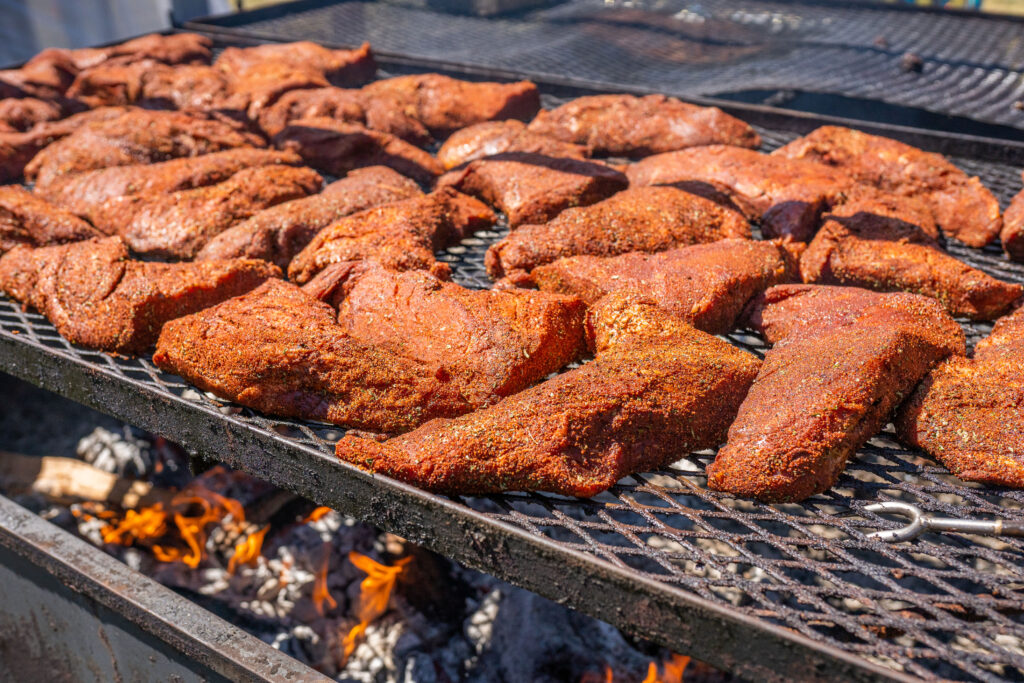 Tritips cooking on open grill with smoke chips in the fire.