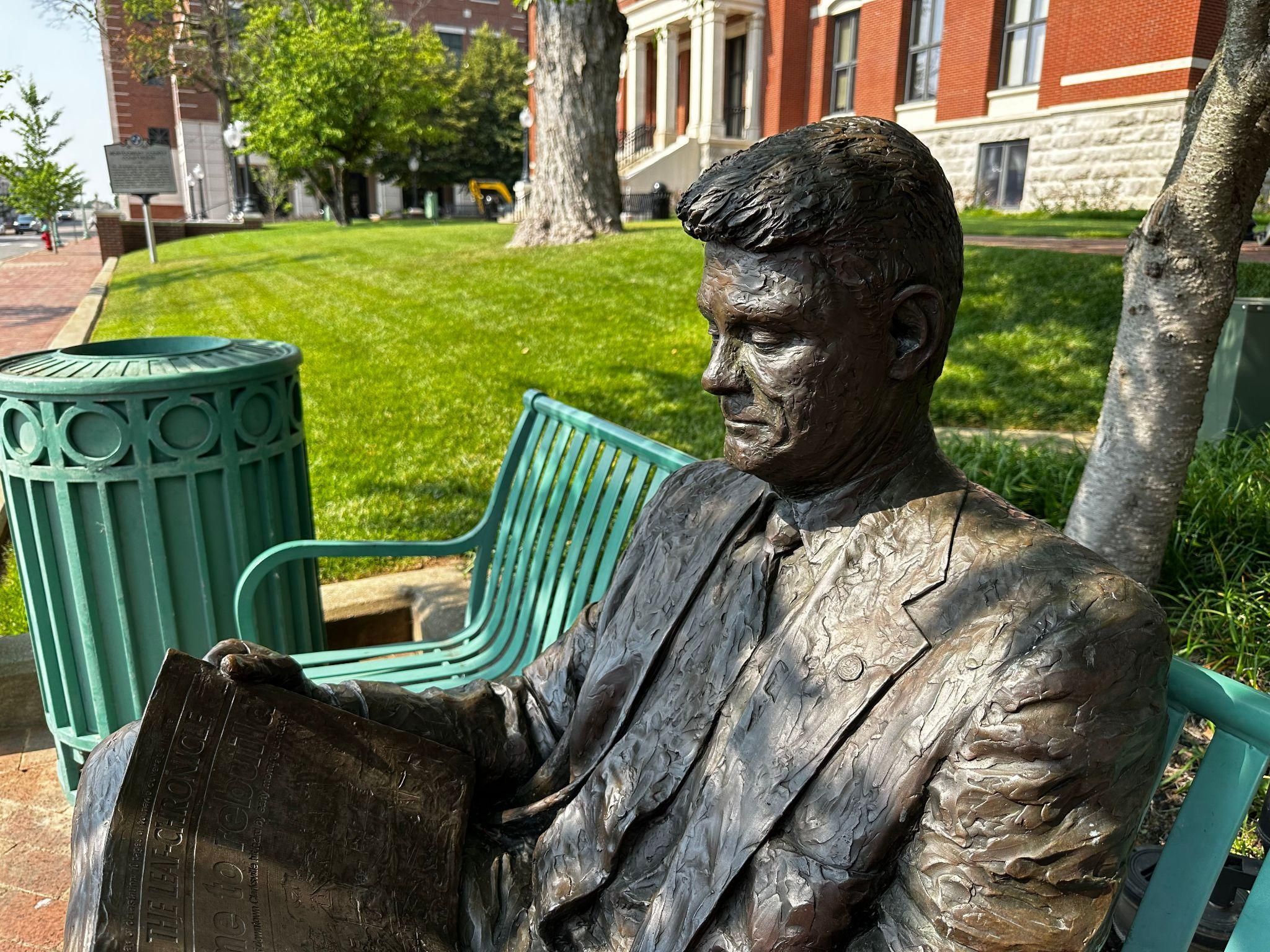 A statue of a man reading a paper.