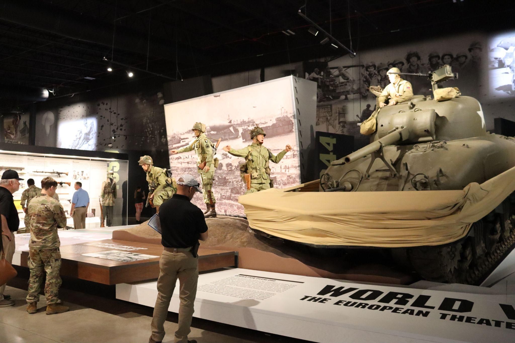 Three men looking at a World War II Exhibit. 