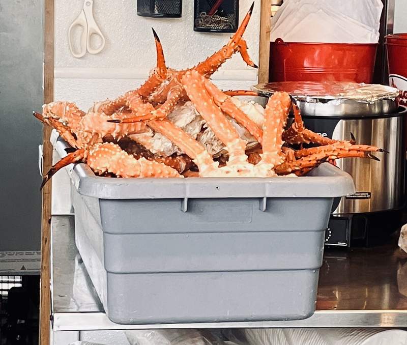 A hard plastic container with many Alaskan King Crab legs.