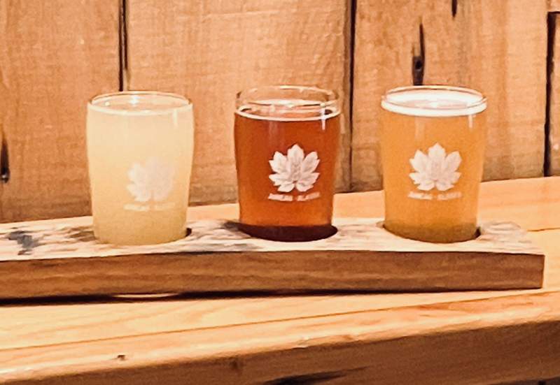 A flight of three beers on a wooden table from Devil's Club Brewing Company.