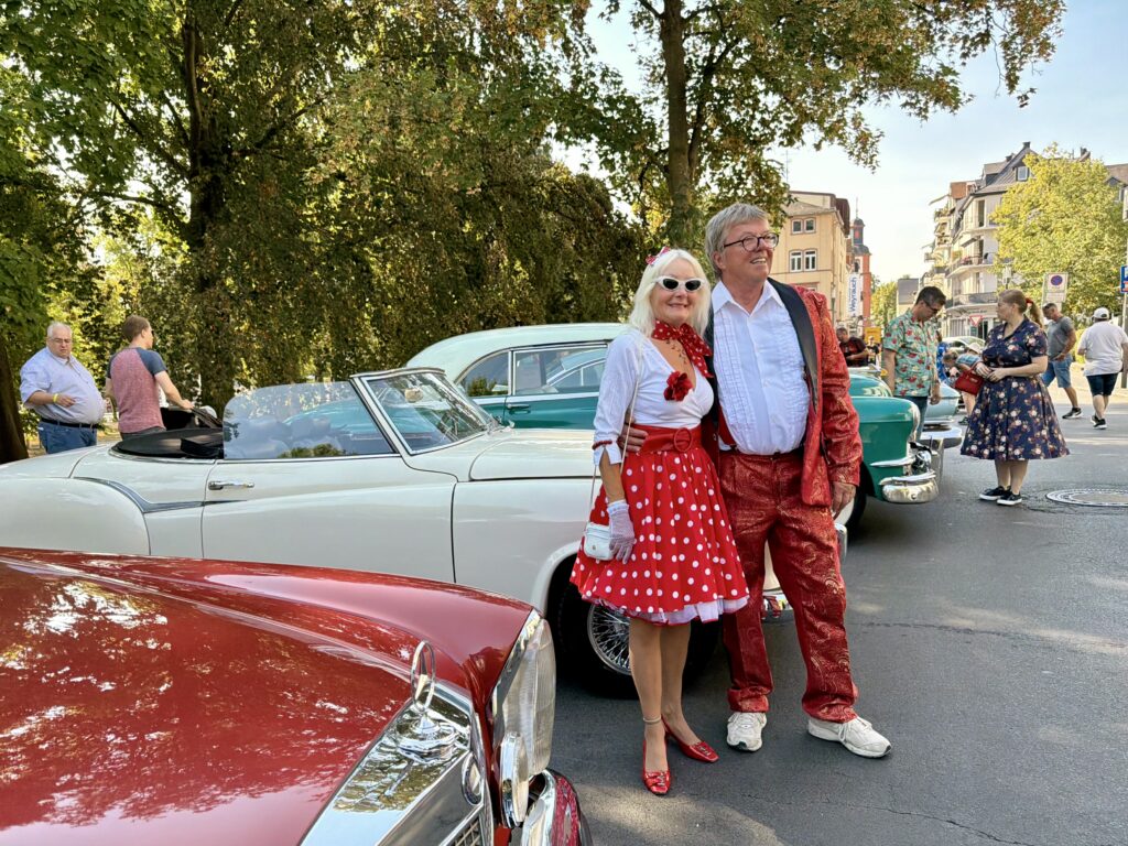 50s couple standing in front of a red classic car in Bad Nauheim at the European Elvis Festival