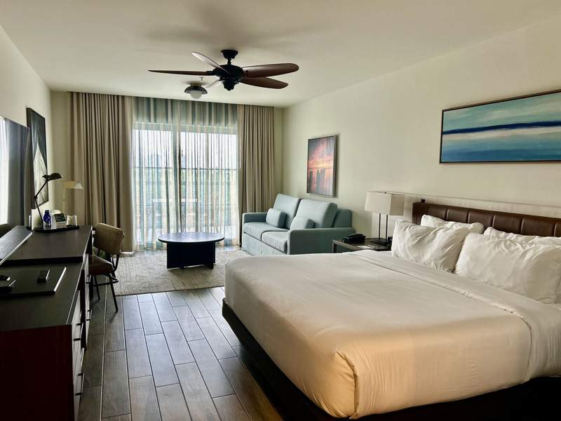 Riverview Balcony Room complete with modern amenities and chic coastal colors, king bed, tv, and wooden floors