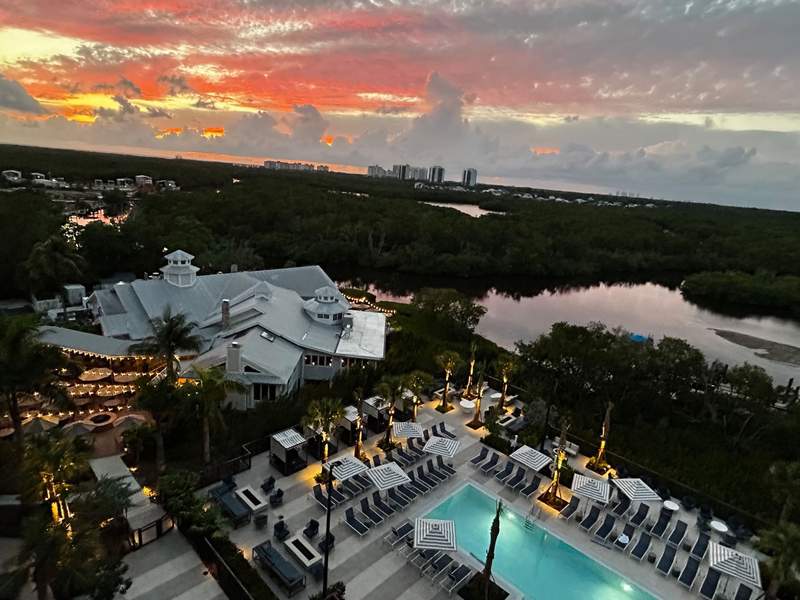 Stunning sunset views on the rooftop of The Perry Hotel Naples, with pool, river, and sparkling lights along the hotel
