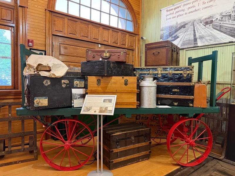 Vintage wagon displaying stacked luggage and travel trunks inside the Cheyenne Depot Museum.