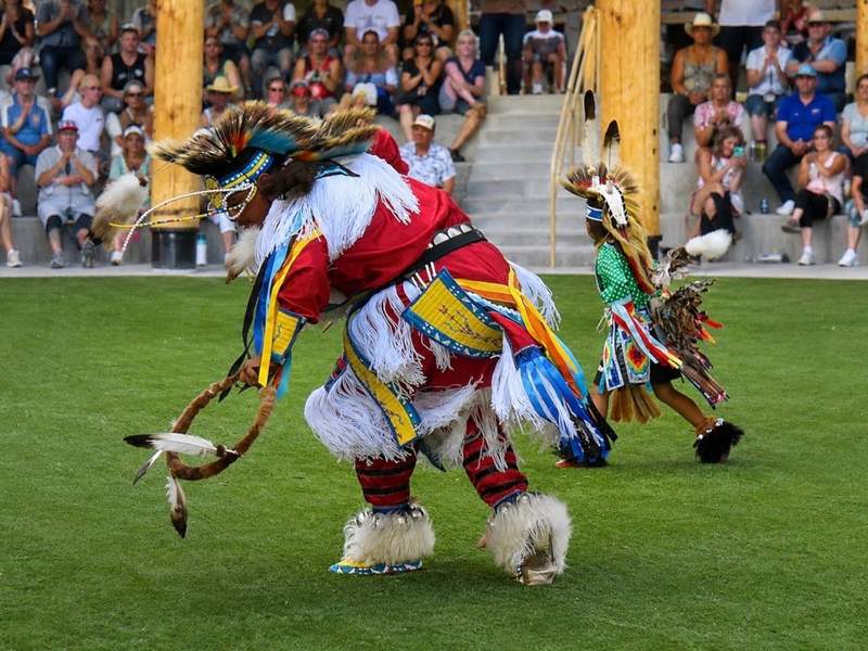 Adult and young Native American dancers in colorful, intricately detailed regalia performing at Morning Star American Indian Village.
