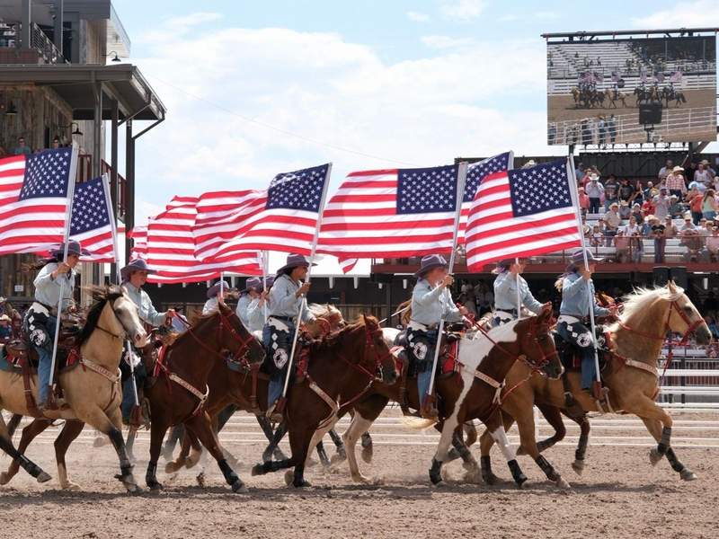 Cowgirls on horseback carrying flags as they ride into the arena during the opening pageantry at Cheyenne Frontier Days. Photo credit: Sharon Kurtz