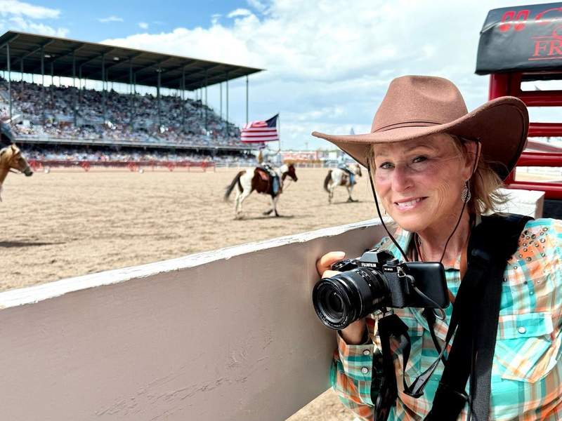 Travel writer and photographer Sharon Kurtz holding her camera behind the chutes at Cheyenne Frontier Days.