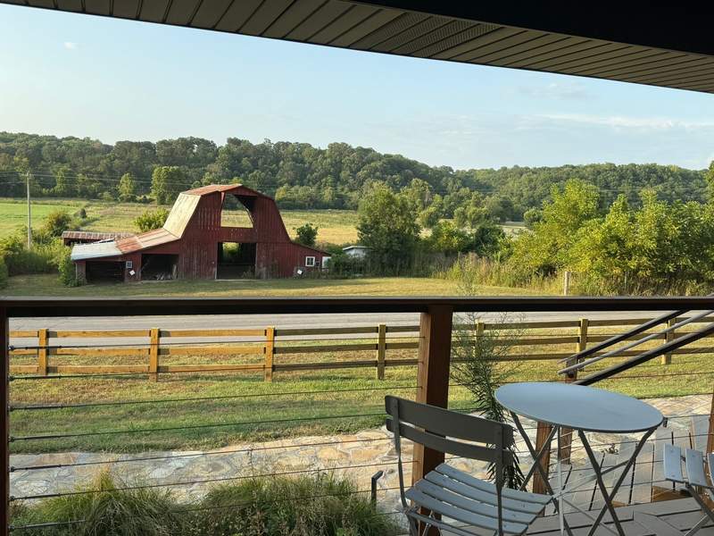 Alt text: The farm to table restaurant Ryn, in Bentonville, features scenic views in the countryside, including a nearby barn and fields.