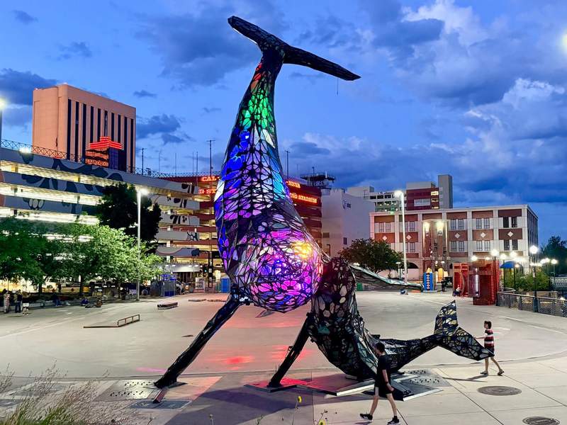 Two boys walk around the enormous Space Whale sculpture in City Plaza at twilight. Space Whale is one of the many public art installations in Downtown Reno.