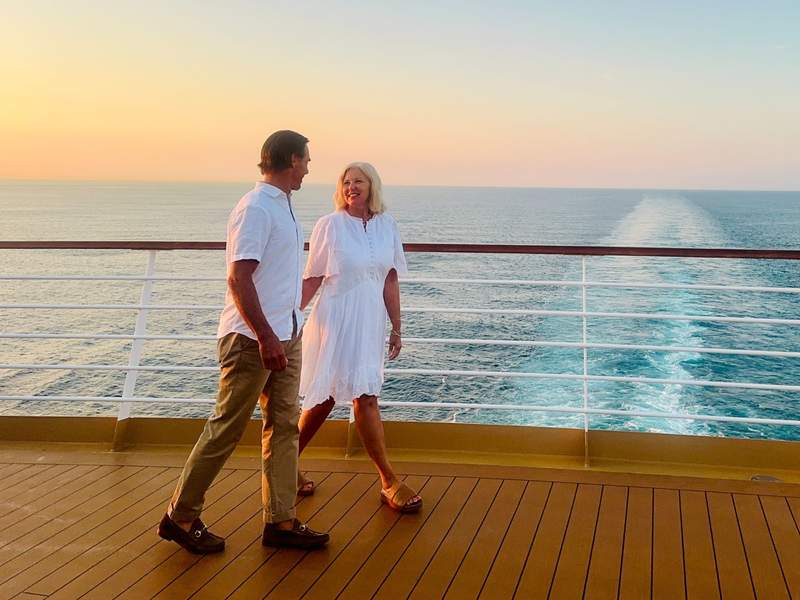 Couple walking on the deck of a Holland America cruise ship at sunset