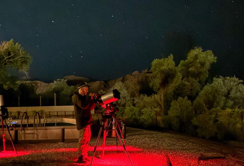 Horizontal night sky view showing stars over the silhouettes of desert rock formations