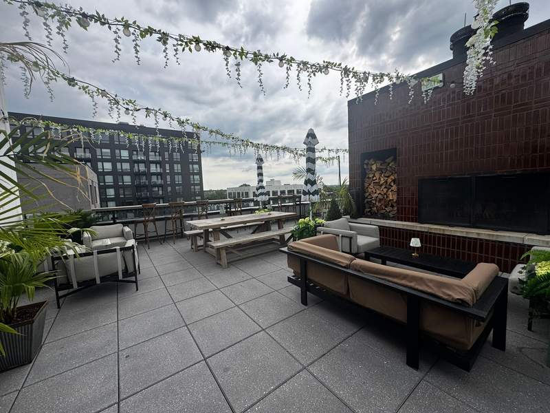 The Junto's outdoor rooftop seating area at Brass Eye, featuring comfortable lounge seating, greenery, and city views.