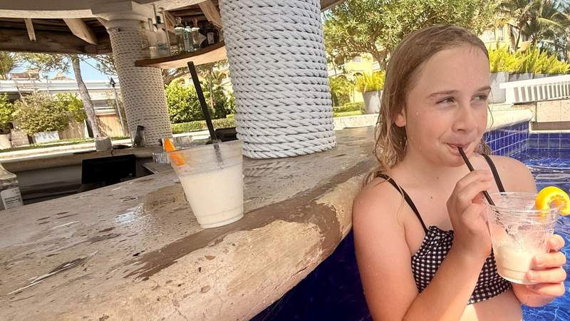 Pre-teen girl drinking a frozen drink at a swim-up bar at Grace Bay Club, Turks & Caicos