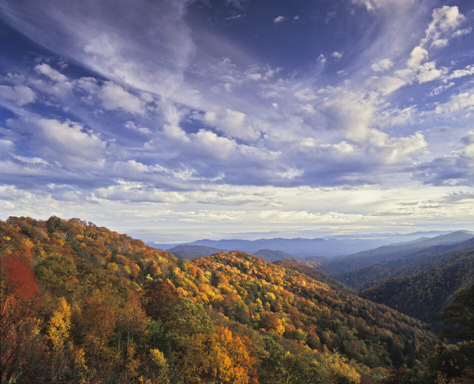 Mountains in fall against a blue sky with clouds.