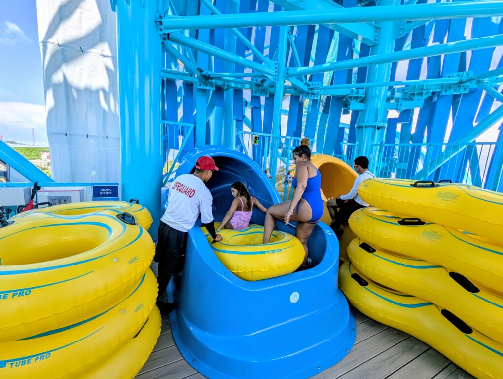 Two women clibming into an innertube to ride a waterslide at Great Tides Waterpark at Norwegian Cruise LIne's private island, Great Stirrup Cay.