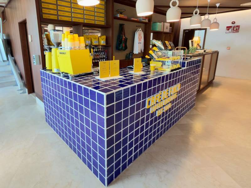 Blue-tiled coffee bar with a yellow espresso machine in the lobby