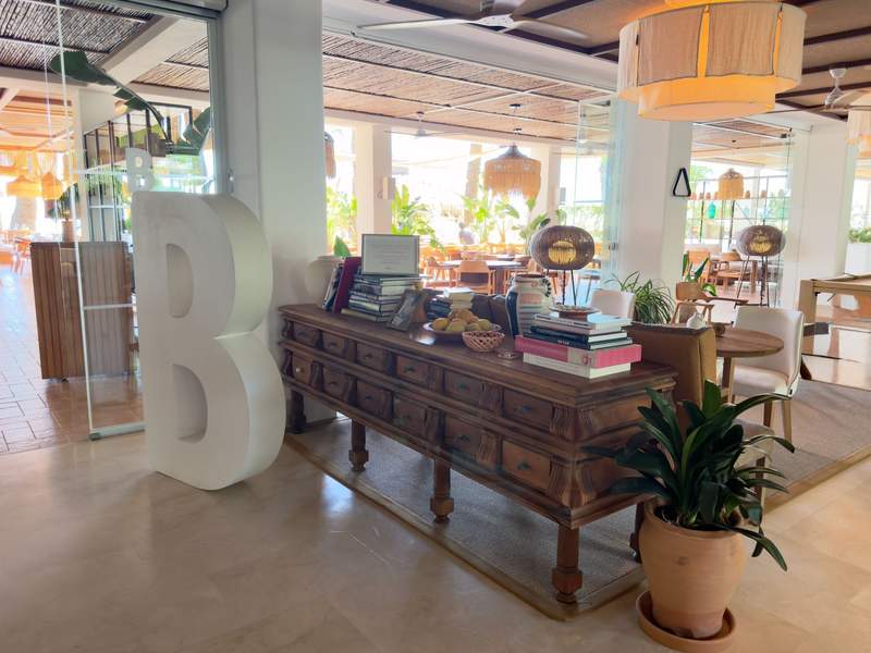 Lobby with a wooden console table, books, plants and open-air seating beyond