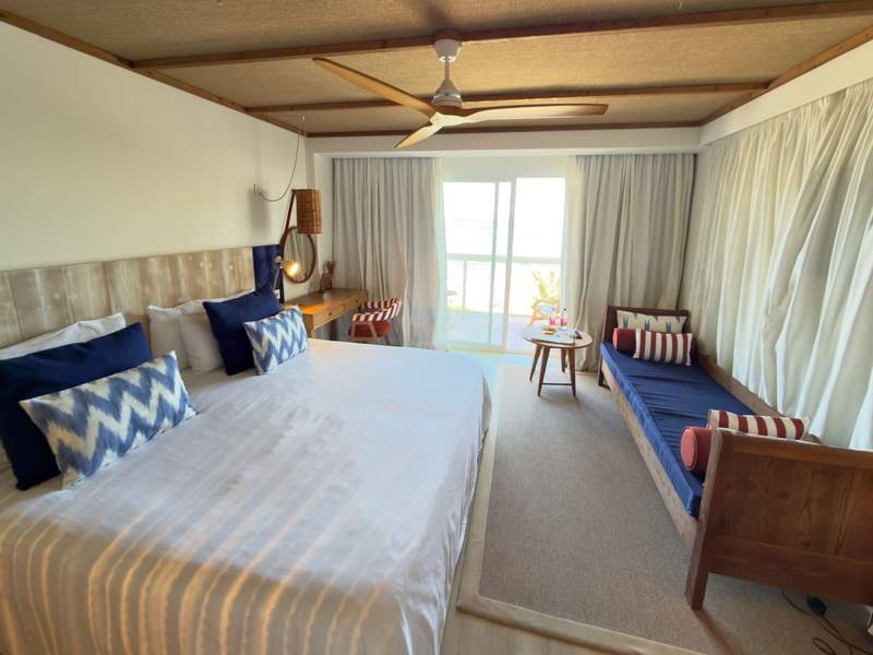 Premier guest room with king bed, blue seating, desk and balcony overlooking the Med.