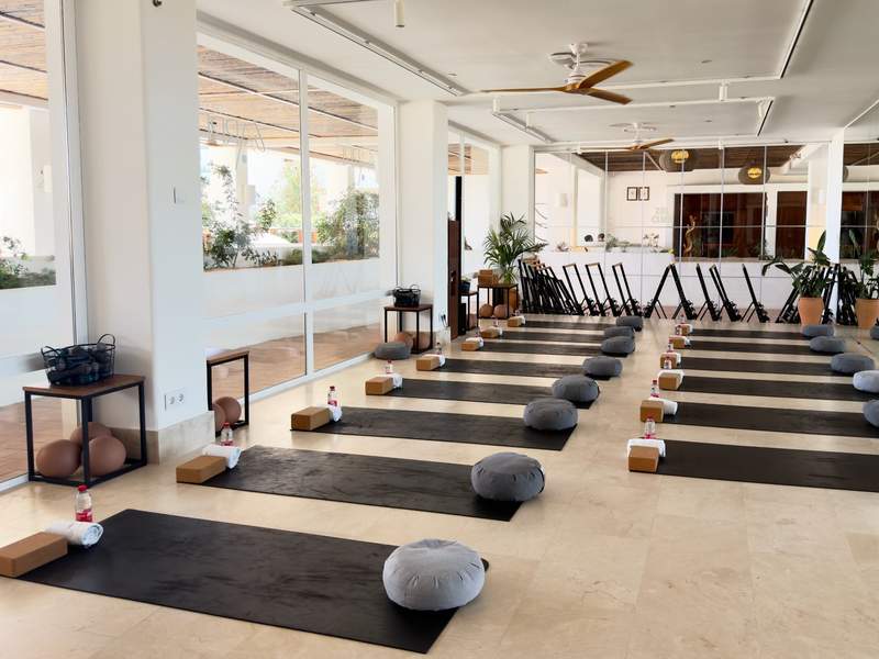 Bright wellness studio set with yoga mats, cushions, blocks, towels and water bottles