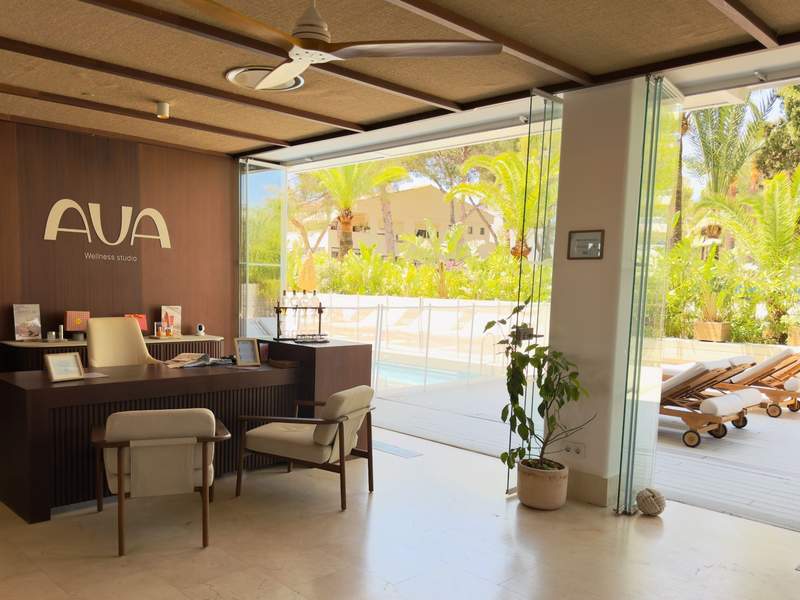 AVA Wellness Studio reception area with glass doors opening to palm trees and outdoor lounge chairs