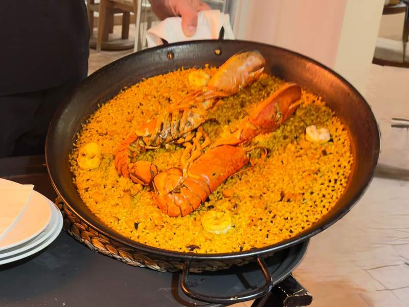 Large pan of paella topped with a whole lobster and shrimp at Beso Beach Mallorca
