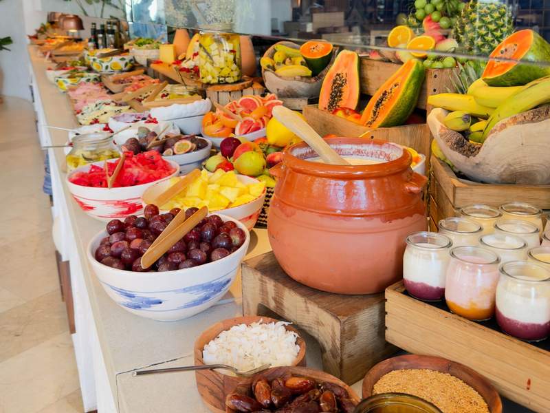 Colorful breakfast buffet with fresh papaya, pineapple, bananas, grapes, yogurt and olives