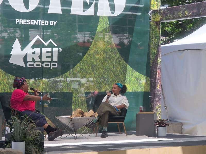 Two women seated on an outdoor stage at Outside Days having a conversation with microphones