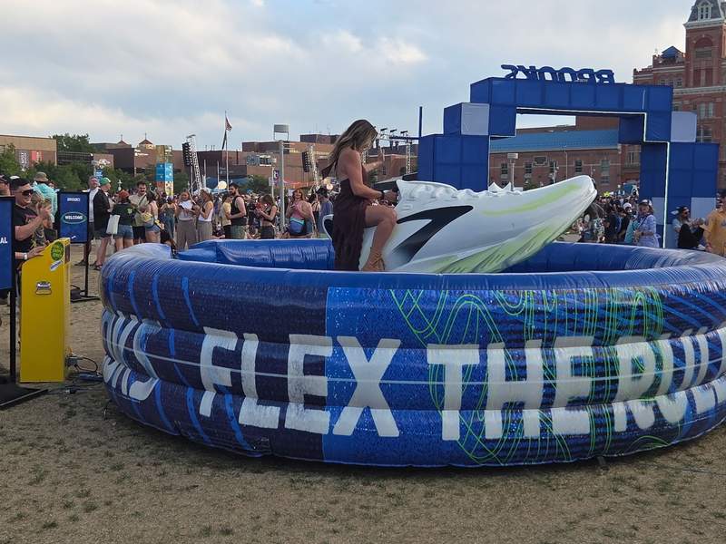 A woman riding an inflatable mechanical bull shaped like a giant sneaker