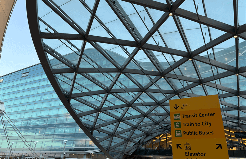Glass and steel airport terminal roof with transit signage