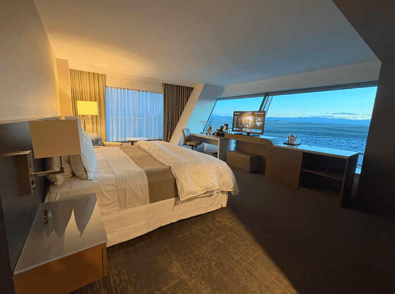 Hotel room with slanted window wall overlooking an airport runway at dusk