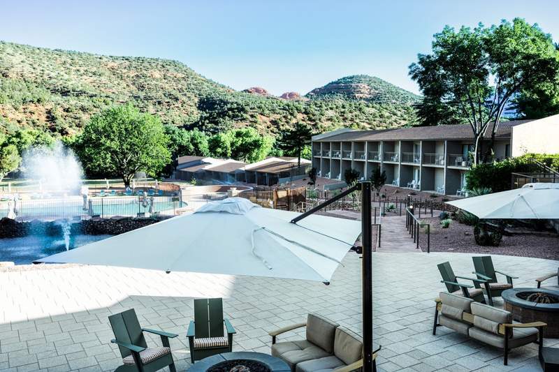 Outbound Sedona pool area with shaded lounge seating, fountains and guest-room buildings framed by red-rock hills.