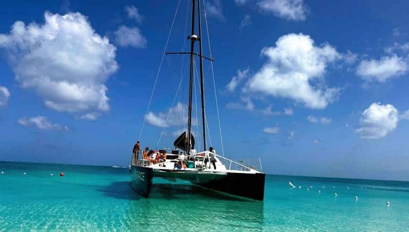Catamaran anchored in shallow turquoise water off a white-sand beach in the Turks and Caicos.