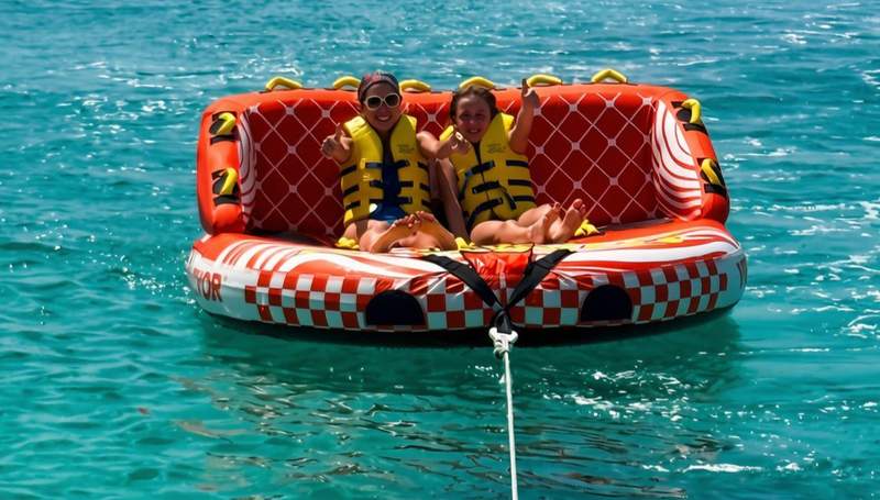 Mother and daughter wearing life jackets on an inflatable tube in the turquoise water off Grace Bay Beach in the Turks and Caicos.