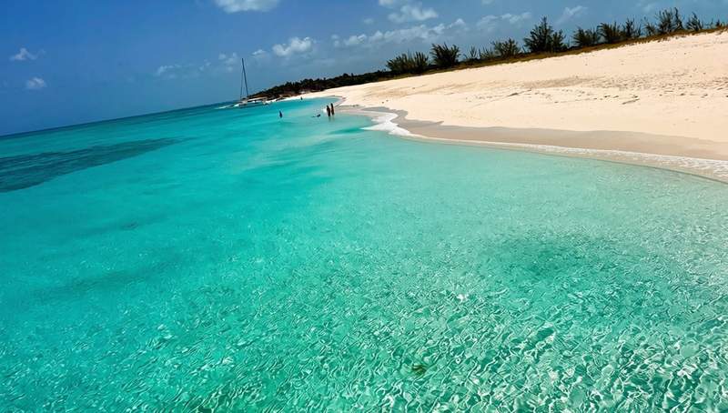 Clear turquoise Caribbean water along a nearly empty white-sand beach in the Turks and Caicos.