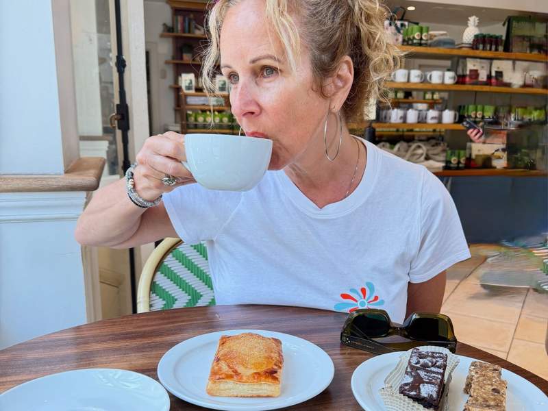 Kim Orlando sips coffee beside a flaky golden pastry, chocolate brownie and nutty snack bar at Honolulu Coffee in Waikiki.