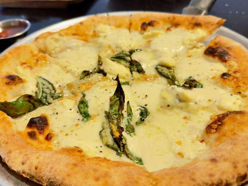 A bubbling wood-fired pizza arrives with a blistered golden crust, melted cheese and fresh basil at Appetito in Waikiki.