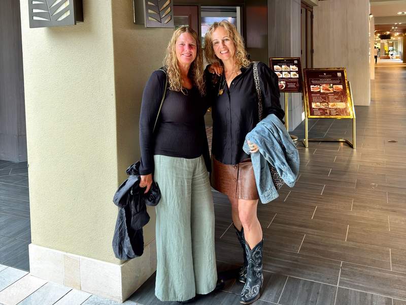 Two friends smile outside Wolfgang’s Steakhouse in Waikiki, dressed for dinner during an Oahu girls trip