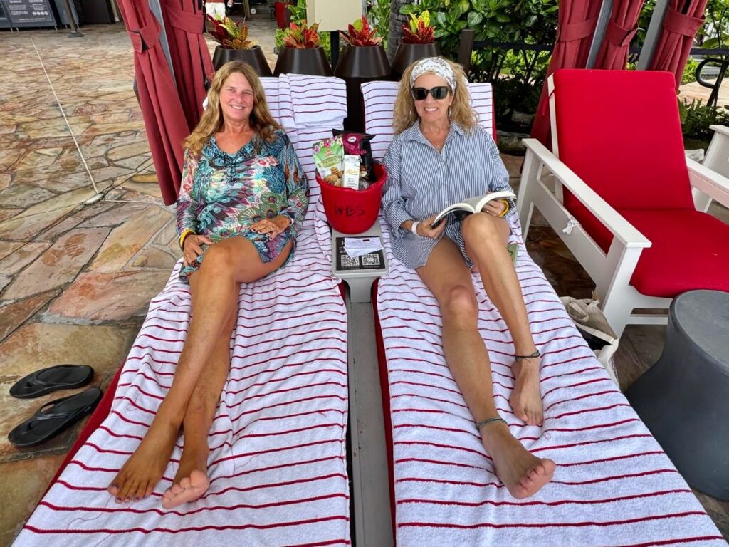 Girls trip includes relaxing side by side on striped lounge chairs under red cabanas at the Sheraton Waikiki]