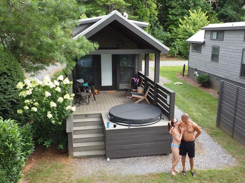 Cabin with a man and woman in bathing attire in front of a covered hot tub.
