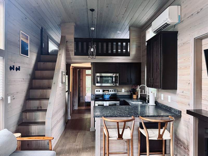 Bright, modern cabin bedroom with a comfortable bed, wood accents and cozy furnishings