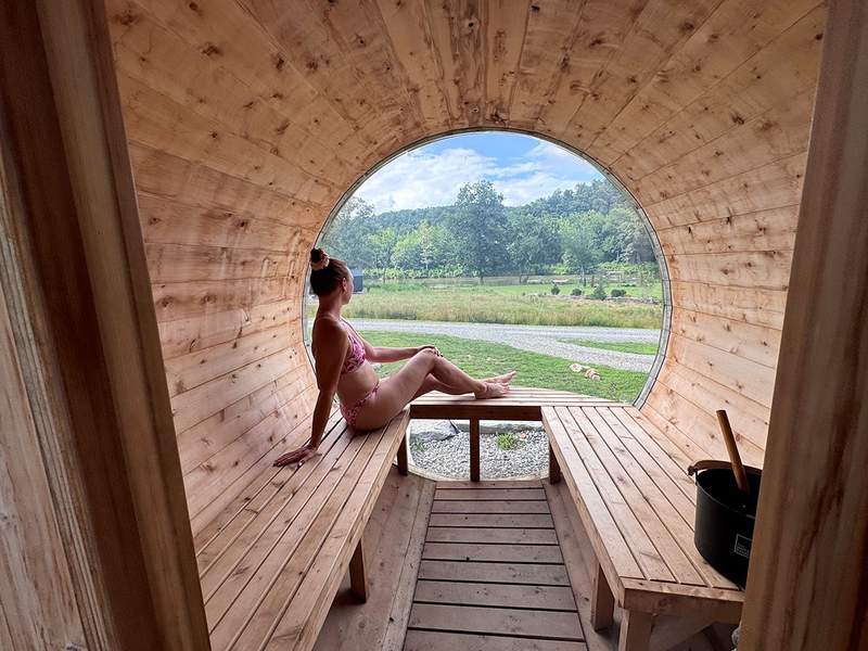 Barrel-shaped wooden sauna overlooking the French Broad River and surrounding trees