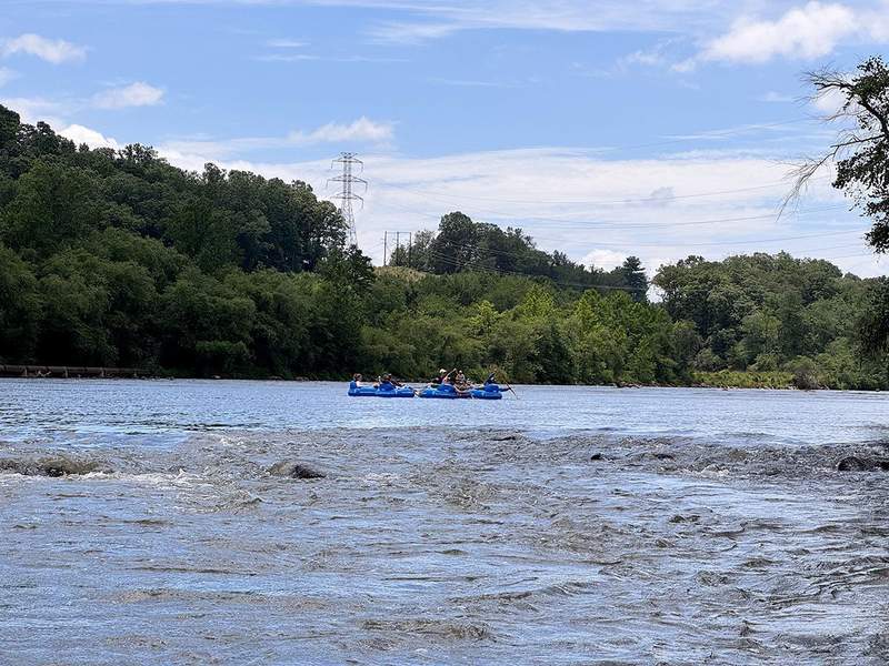 A group of people floating down the French Broad River on tubes with Zen Tubing