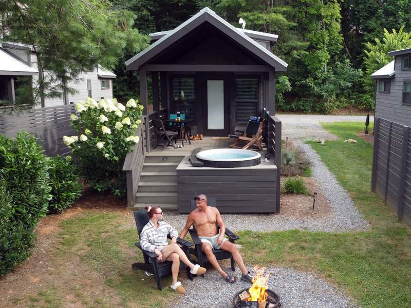Man and woman in front of a fire pit with a hot tub in the background.