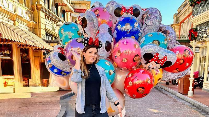Woman wearing polka dot Minnie Mouse ears in front of a balloon bouquet at Disneyland