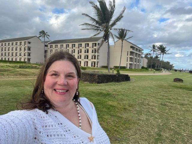 Woman taking selfie in from of a hotel with palm trees